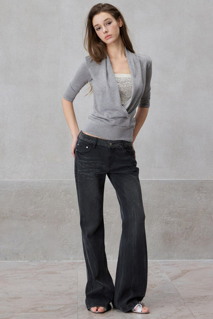Woman wearing a gray cardigan and black jeans against a plain background
