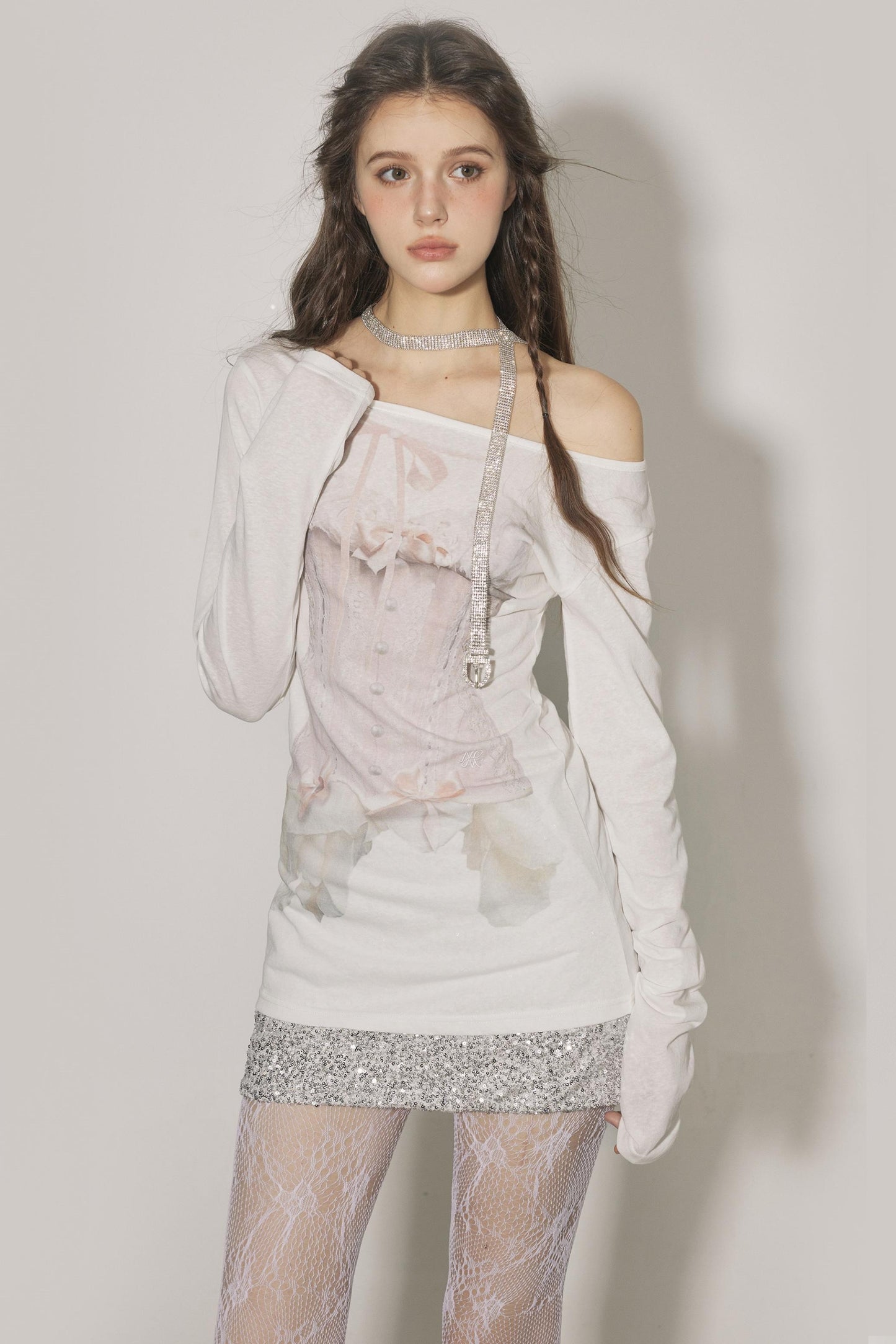 Woman wearing a floral off-shoulder dress with sheer tights against a plain background