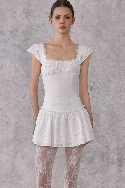 Woman wearing a white lace dress against a gray background