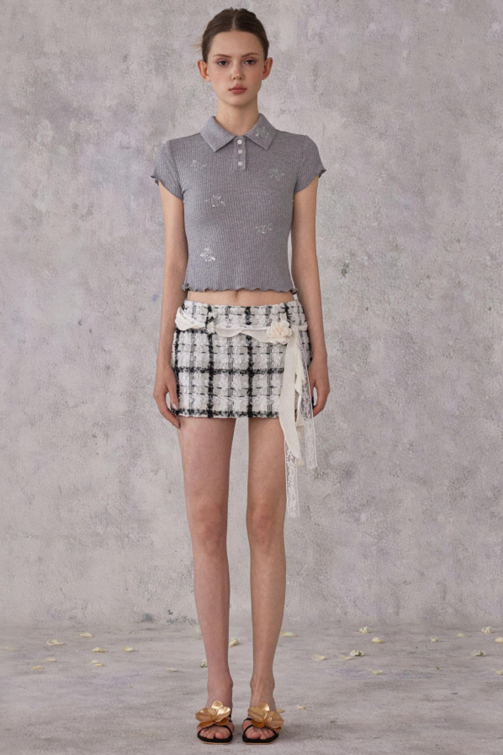 Model wearing a gray patterned top and black and white checkered shorts with a gray background