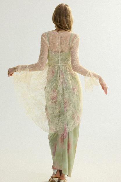 A woman viewed from behind wearing a flowing sheer long-sleeve dress in pale sage green with pink floral accents and a matching sheer overlay, photographed against a plain light background.