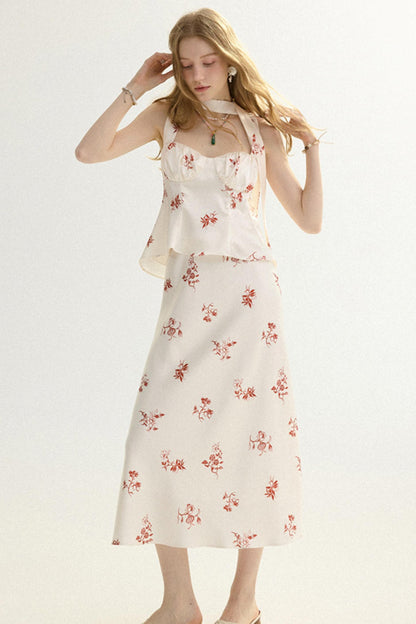 A woman modeling a sleeveless cream dress with a red floral print and a ruffled halter-style bodice, photographed against a plain light background.