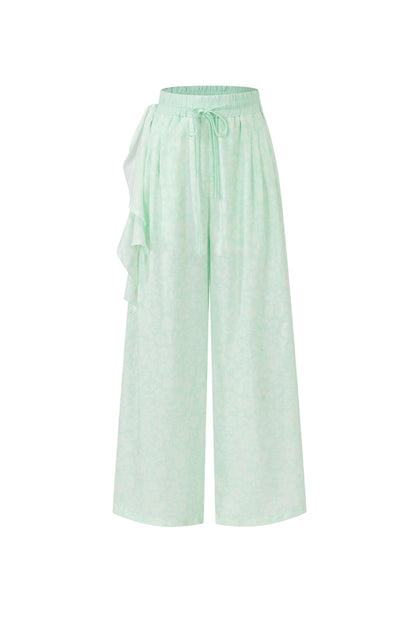 Light mint green wide-leg pants with a drawstring waist and side ruffle detail, shown against a plain white background.