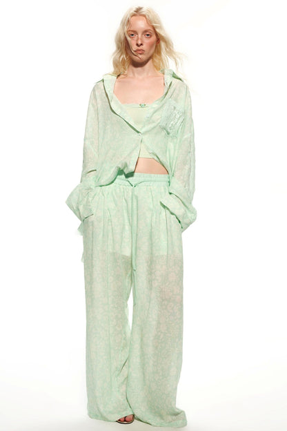 A model wearing a light mint green two-piece outfit consisting of a long-sleeve cropped top and matching wide-leg pants, photographed against a solid white studio background.