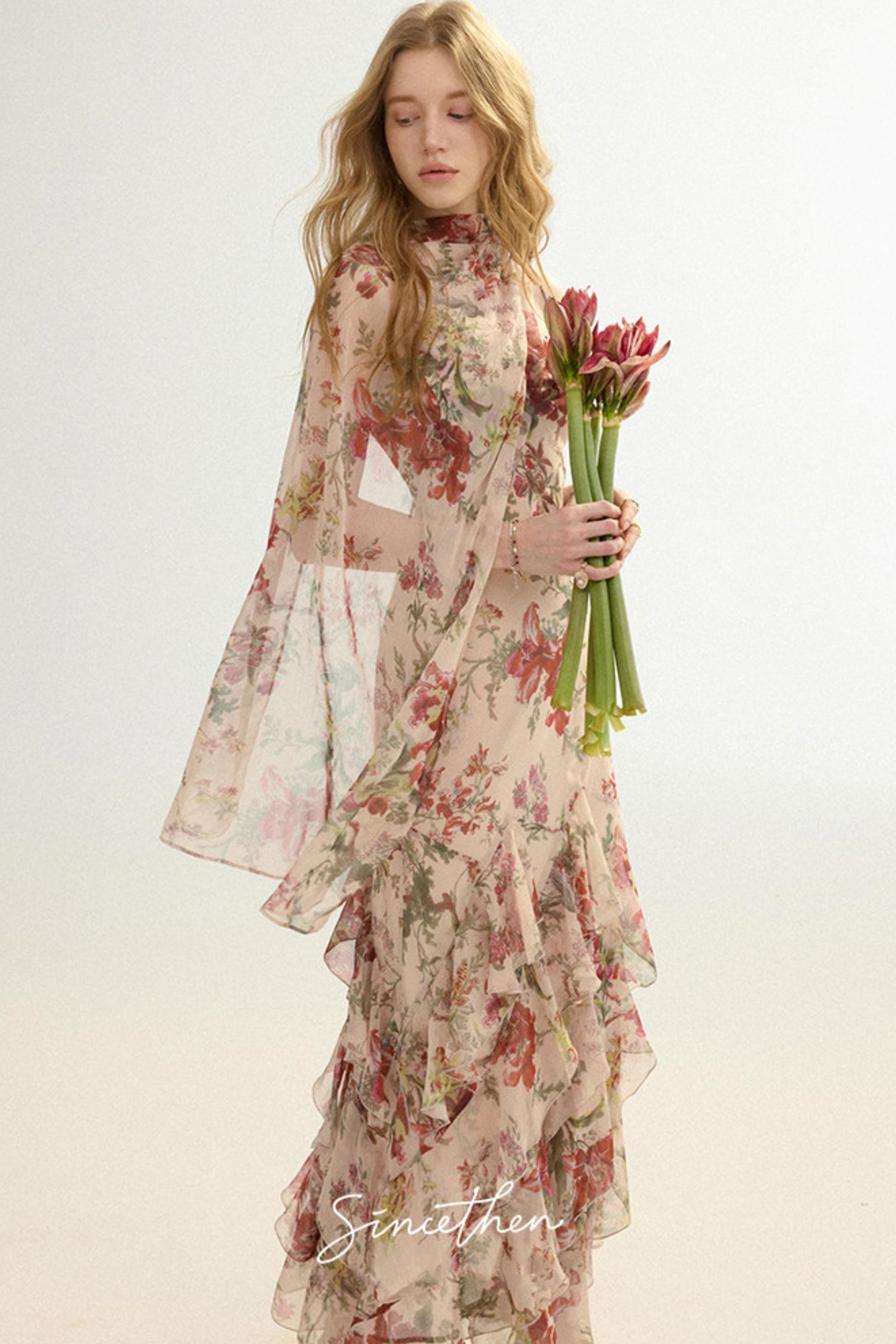 Woman wearing a floral dress holding flowers against a white background