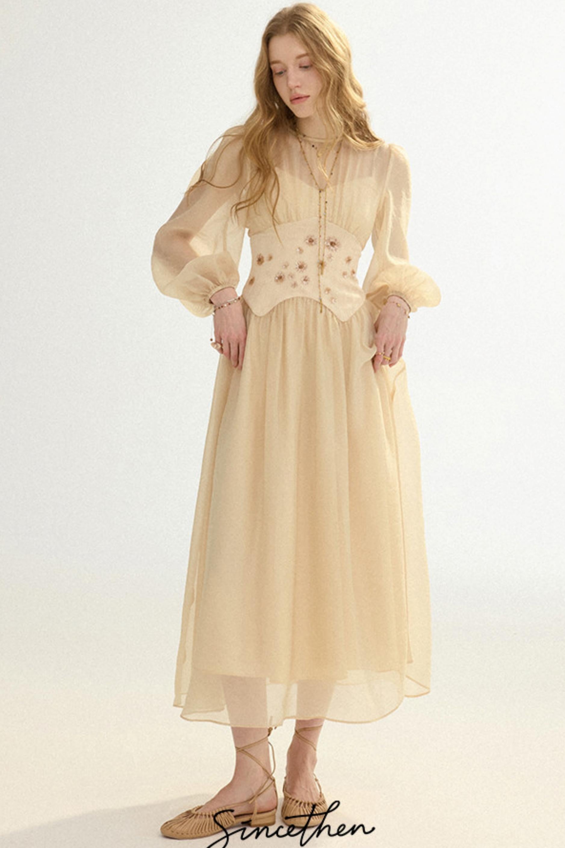 Woman wearing a beige dress with floral embellishments on a white background