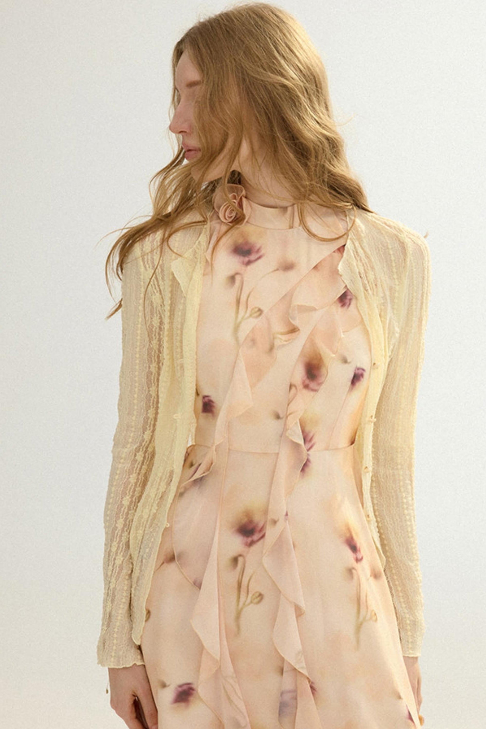 Woman wearing a floral dress with a beige cardigan on a light background
