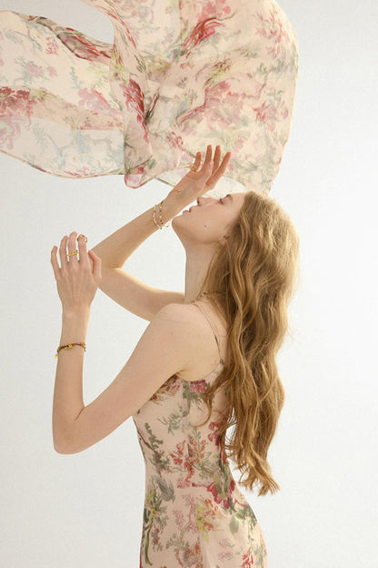 Woman in a floral dress holding a large floral pillow against a white background