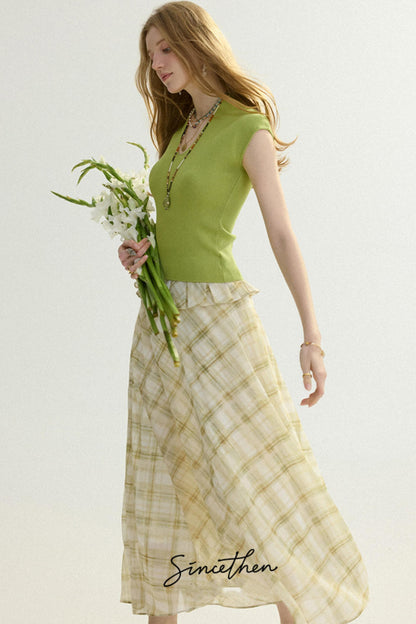 Woman wearing a green top and plaid skirt holding flowers on a white background