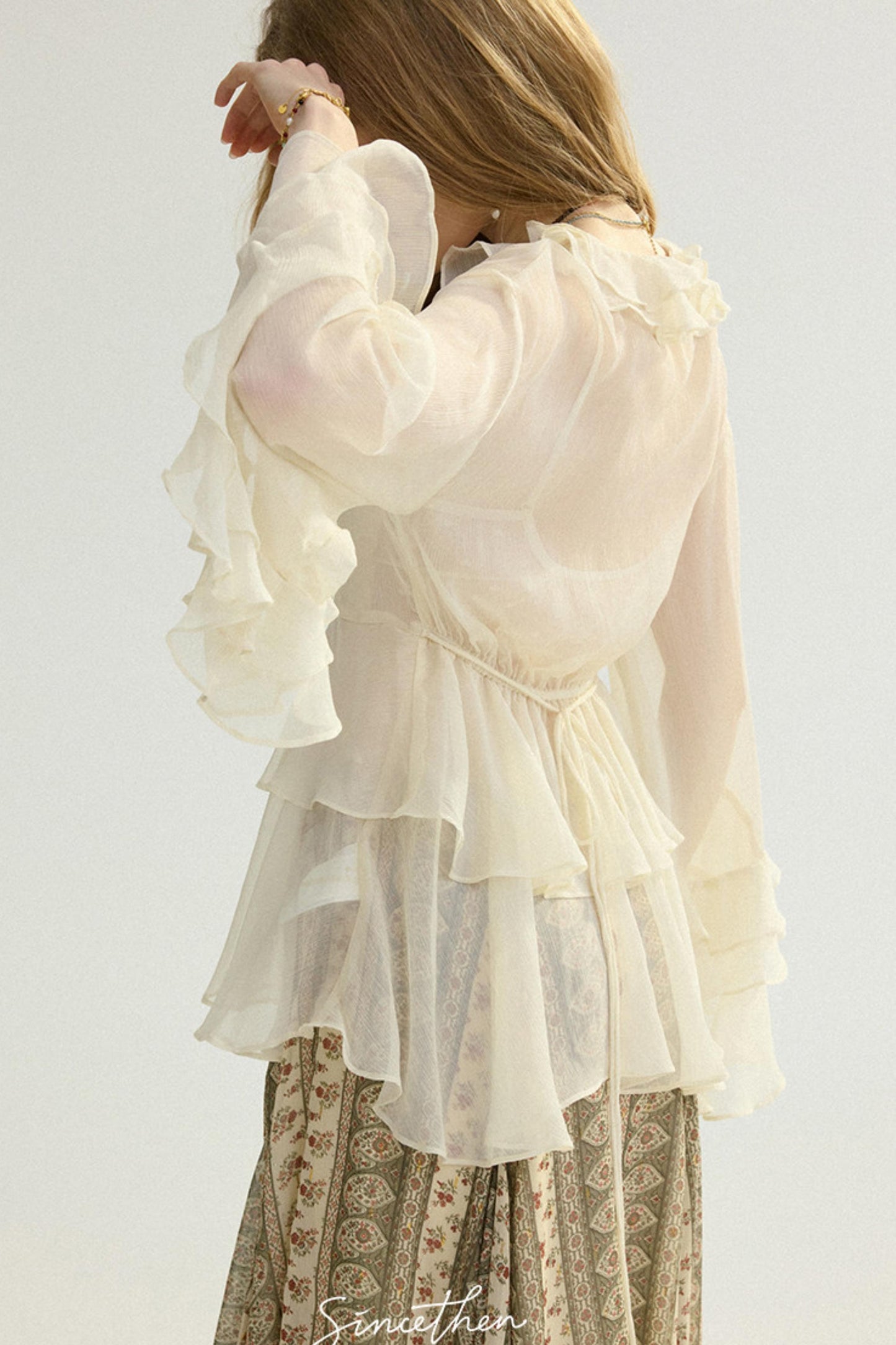 White ruffled blouse worn by a person on a plain background