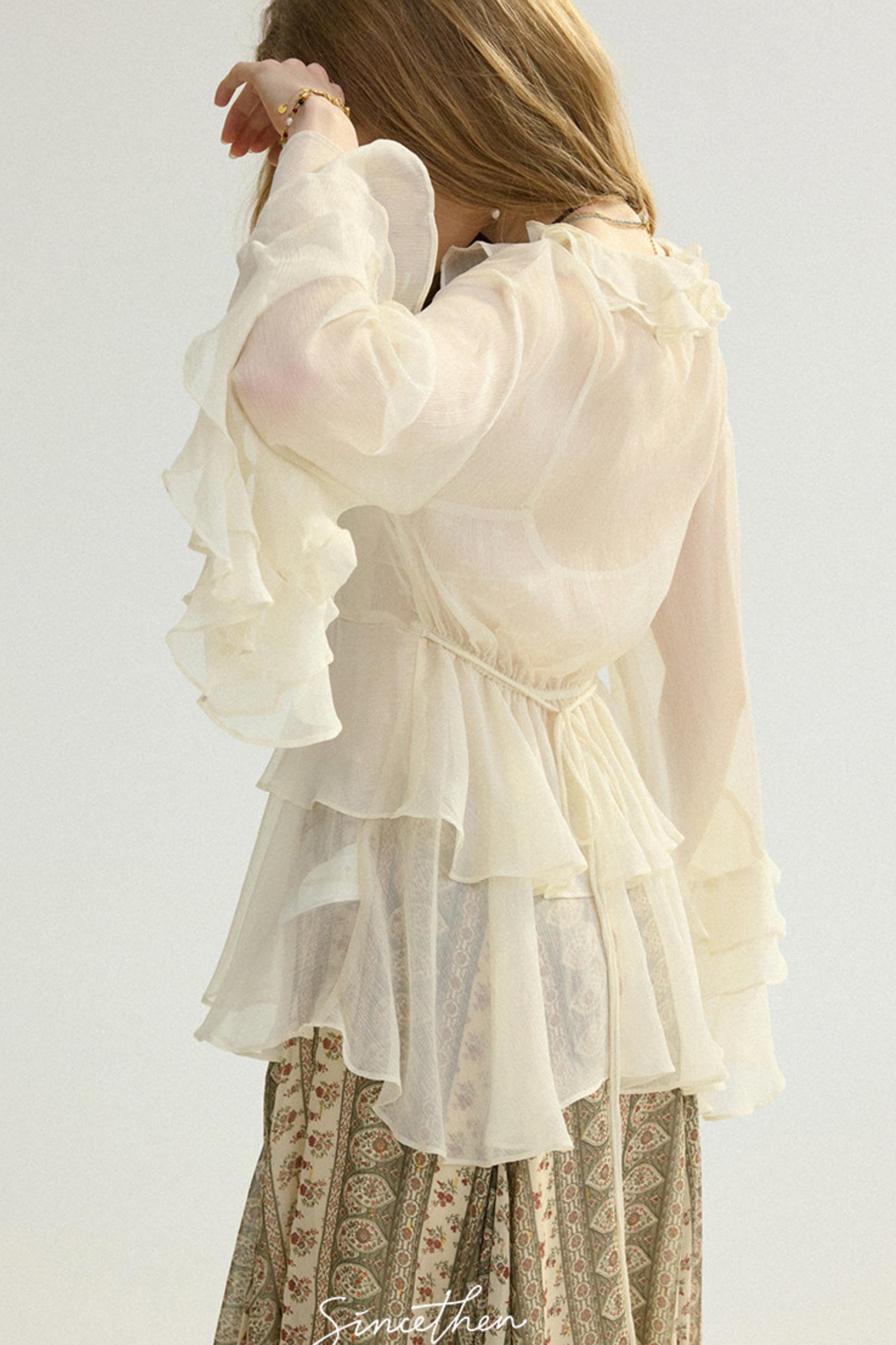 White ruffled blouse worn by a person on a plain background