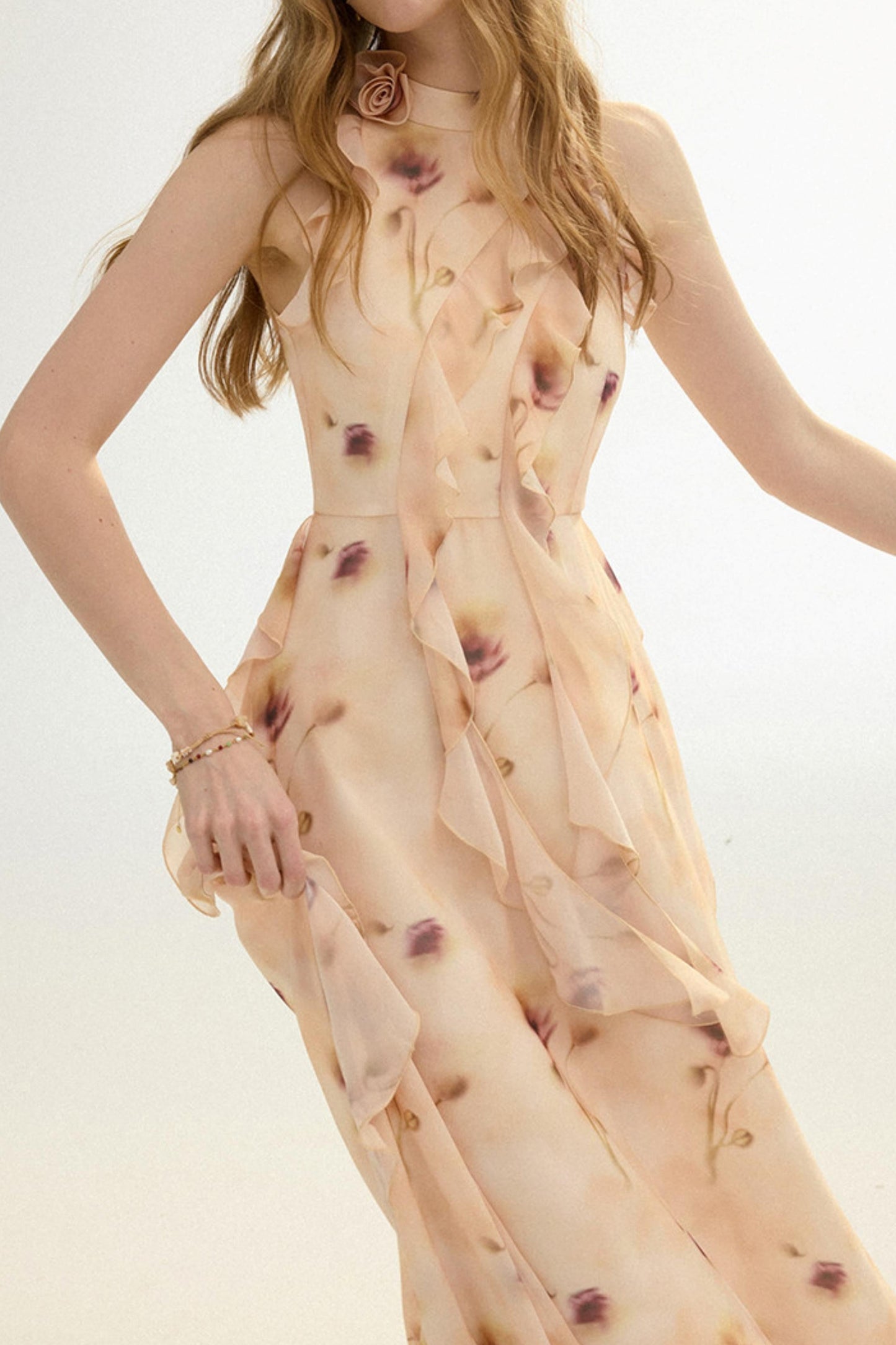 Woman wearing a sheer beige dress with red floral patterns on a light background