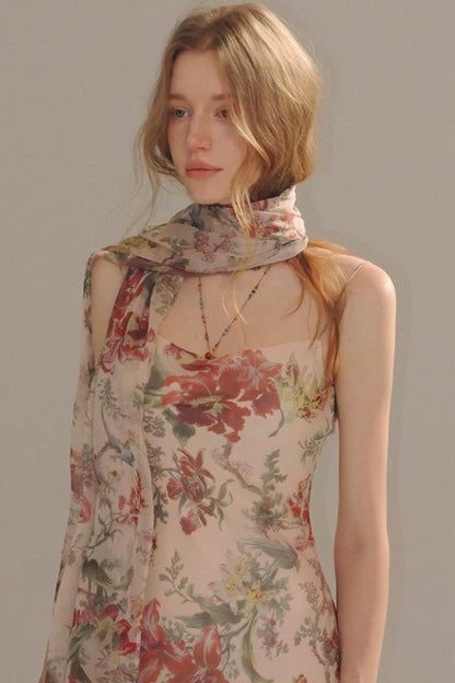 Woman wearing a floral dress with a matching scarf against a plain background