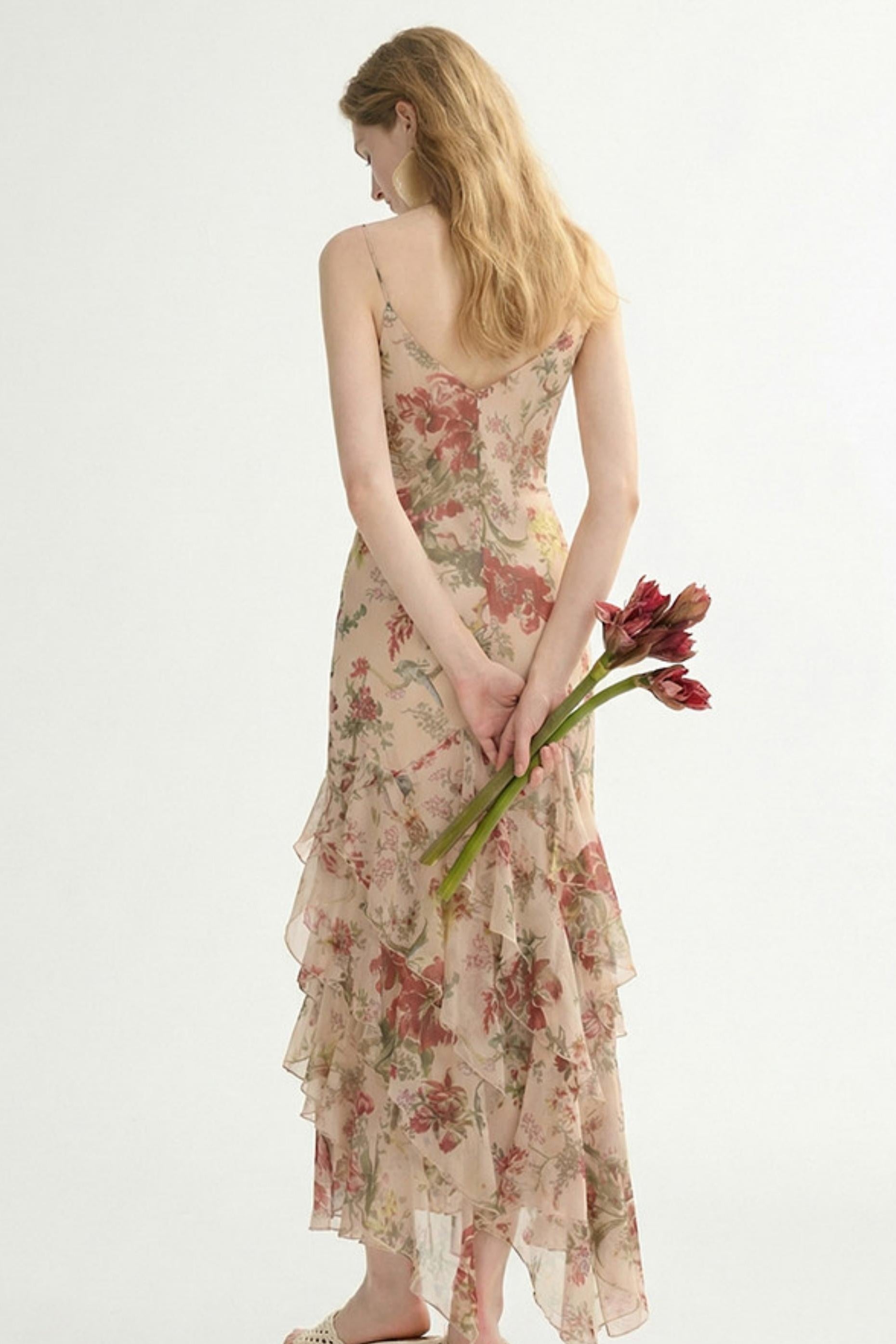 Woman in a floral dress holding tulips against a white background