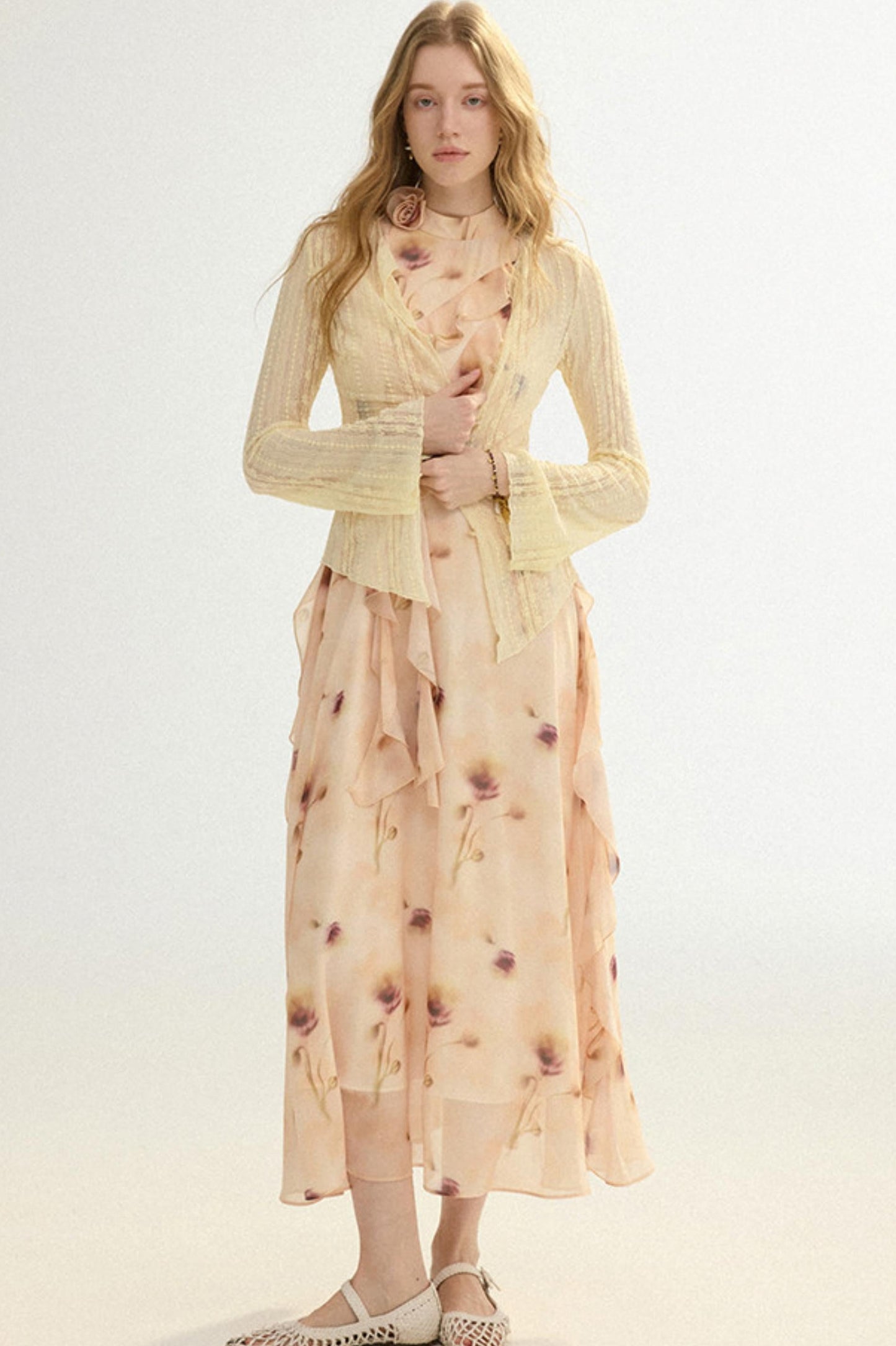 Woman wearing a light yellow cardigan over a floral dress on a white background