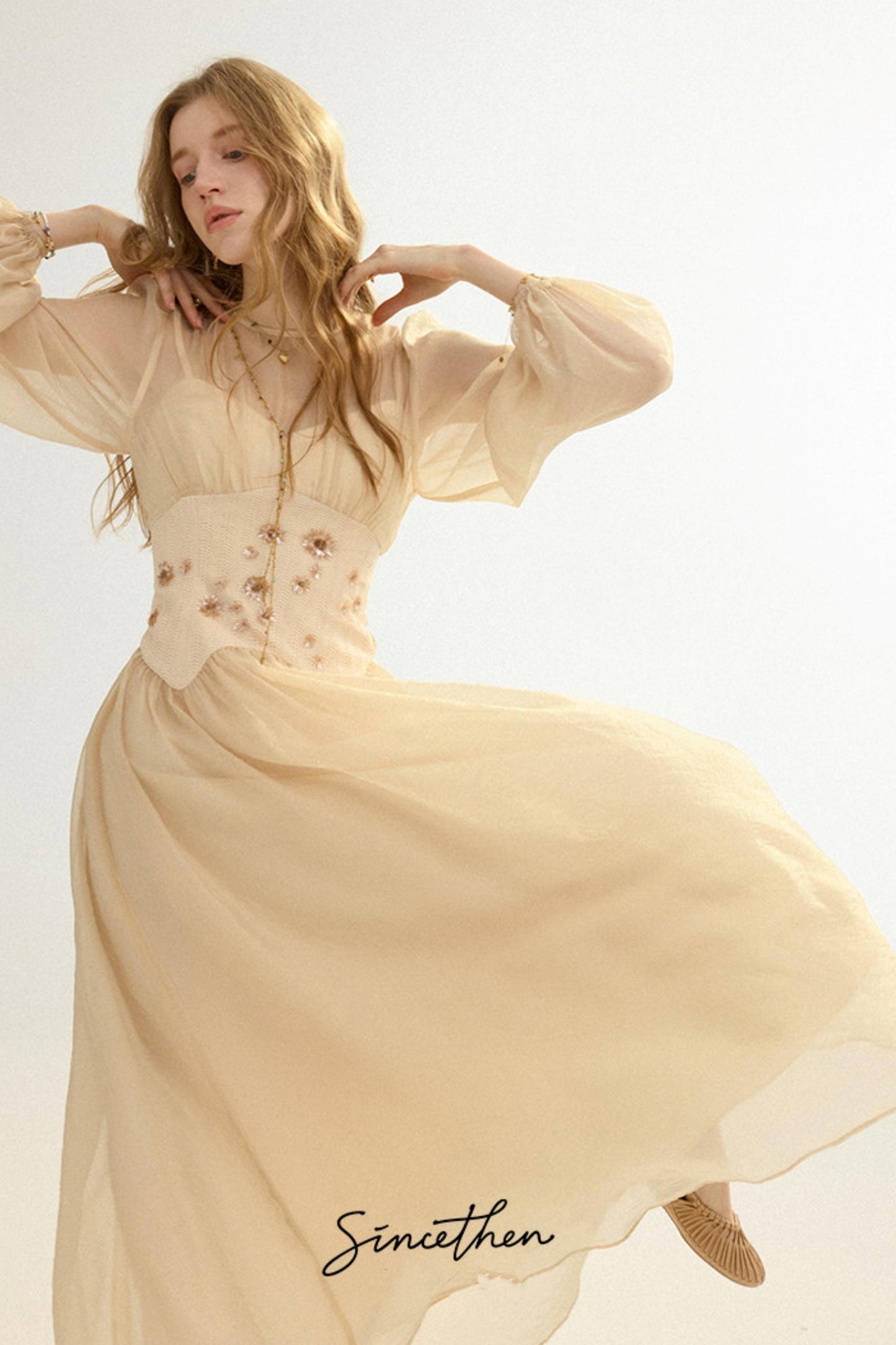 Woman wearing a beige dress with floral embroidery on a light background