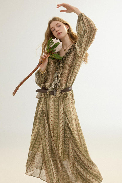 Woman in a long, patterned dress holding a staff and leaves against a light background