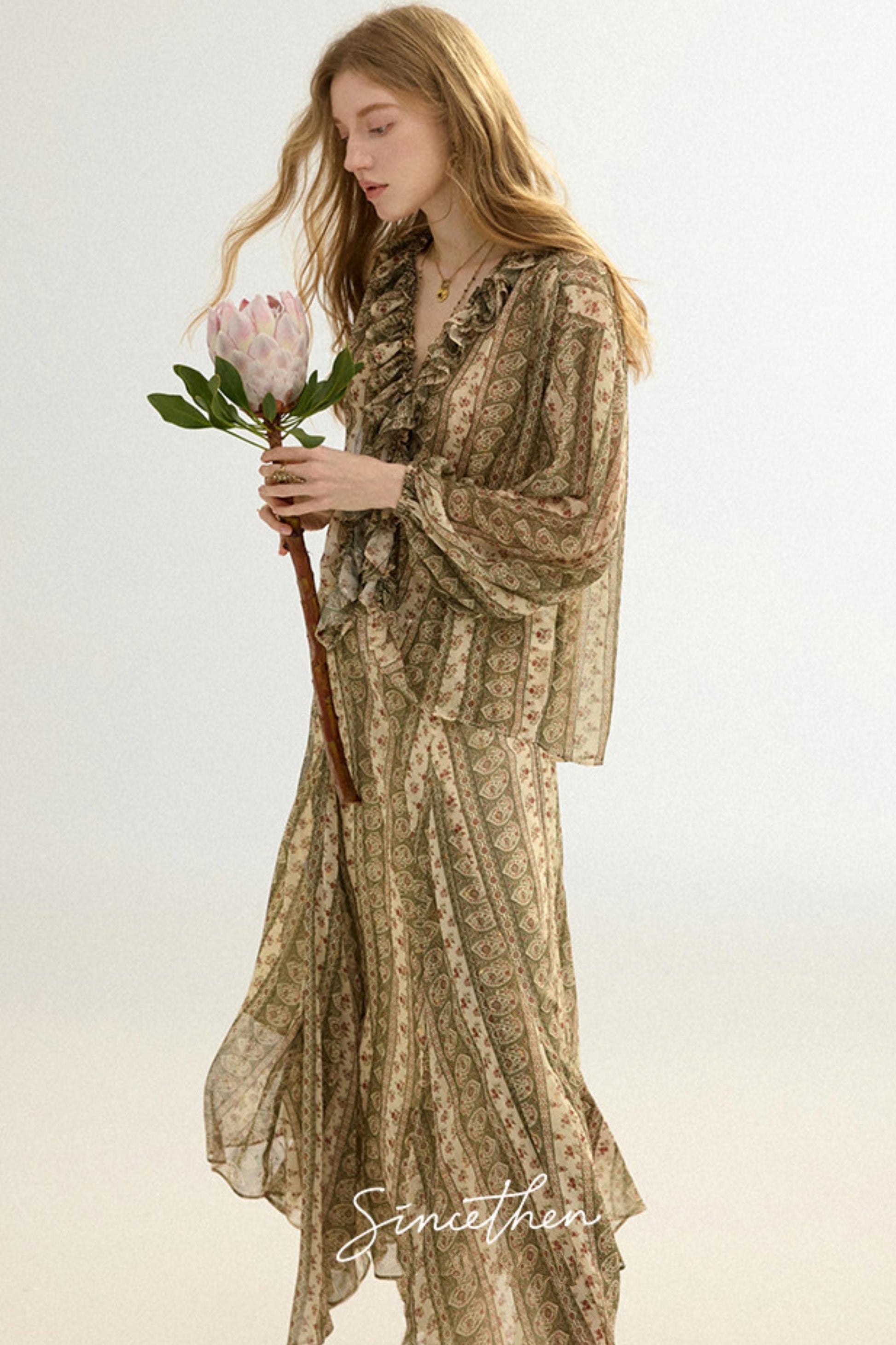 Woman holding a pink flower wearing a patterned dress on a light background