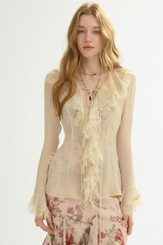 Woman wearing a sheer beige top with floral skirt on a white background