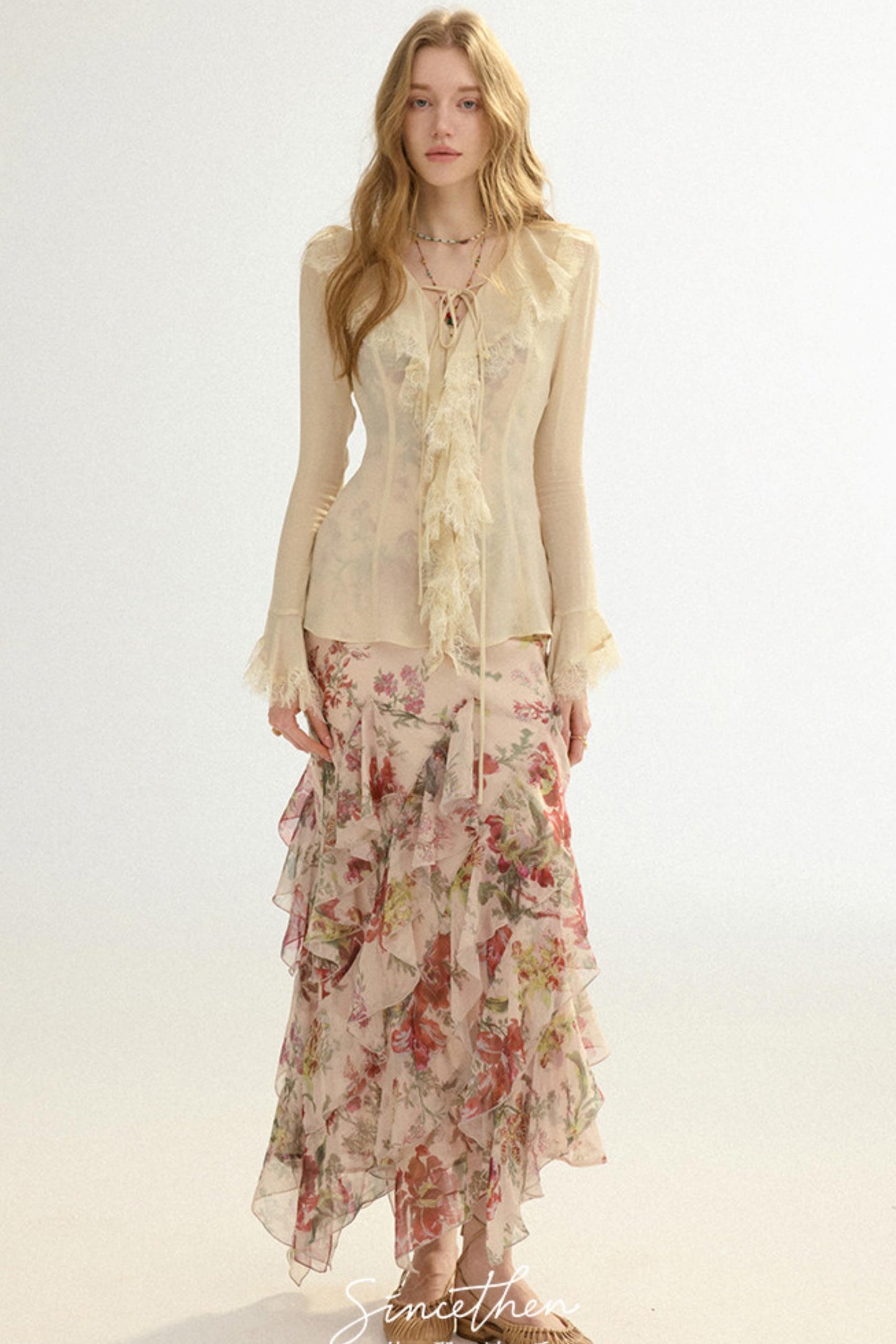Woman wearing a floral dress with a sheer top on a white background