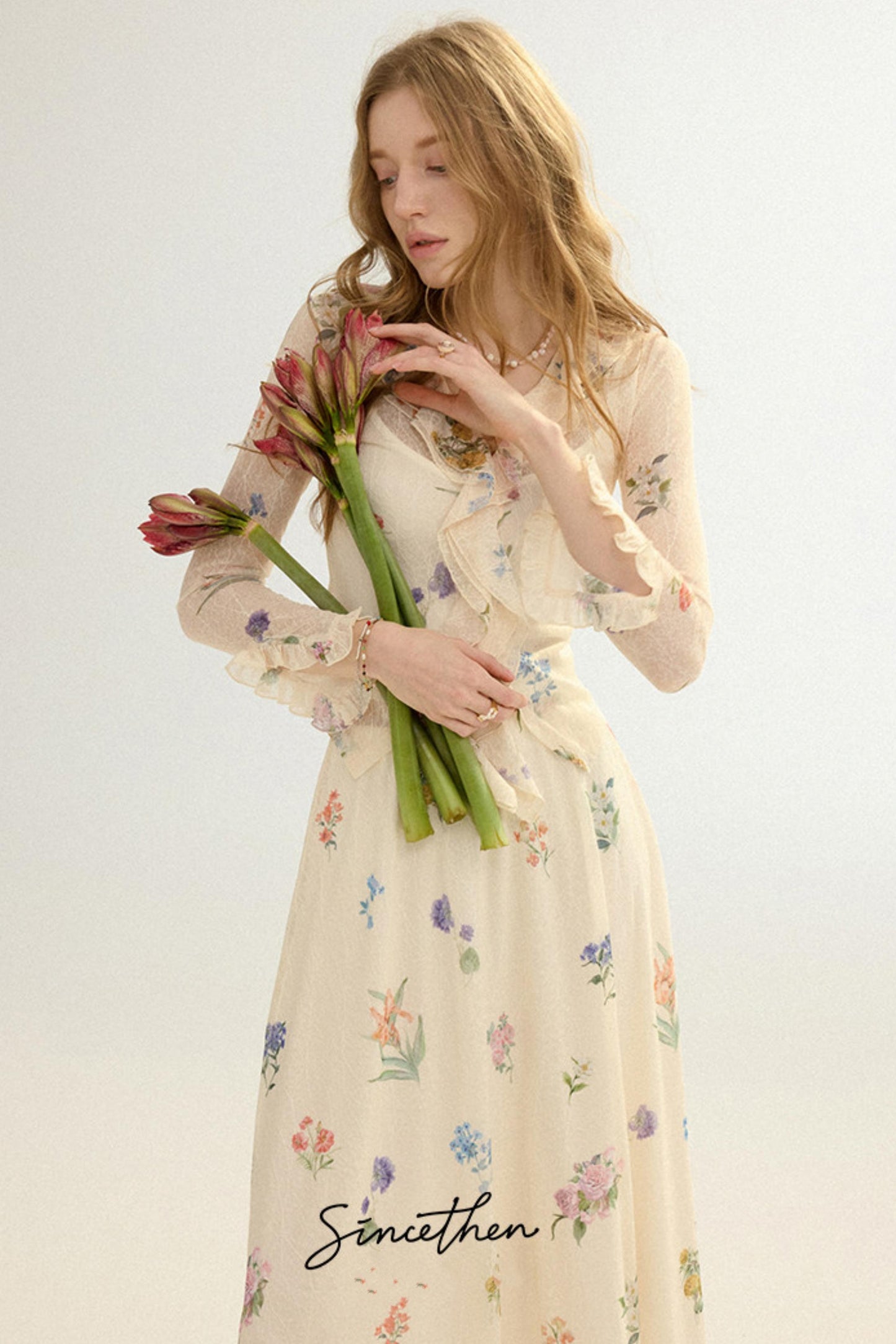 Woman in a floral dress holding flowers against a white background