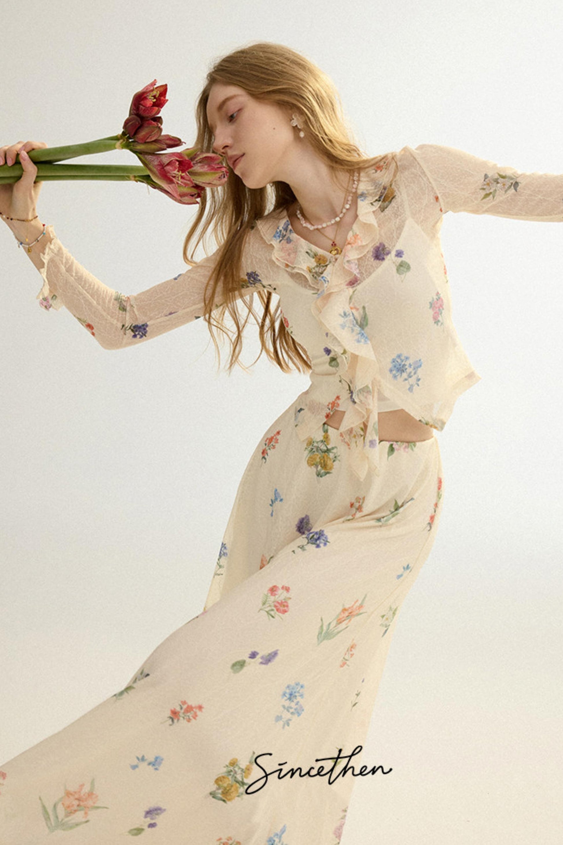 Woman in a floral dress holding tulips against a light background