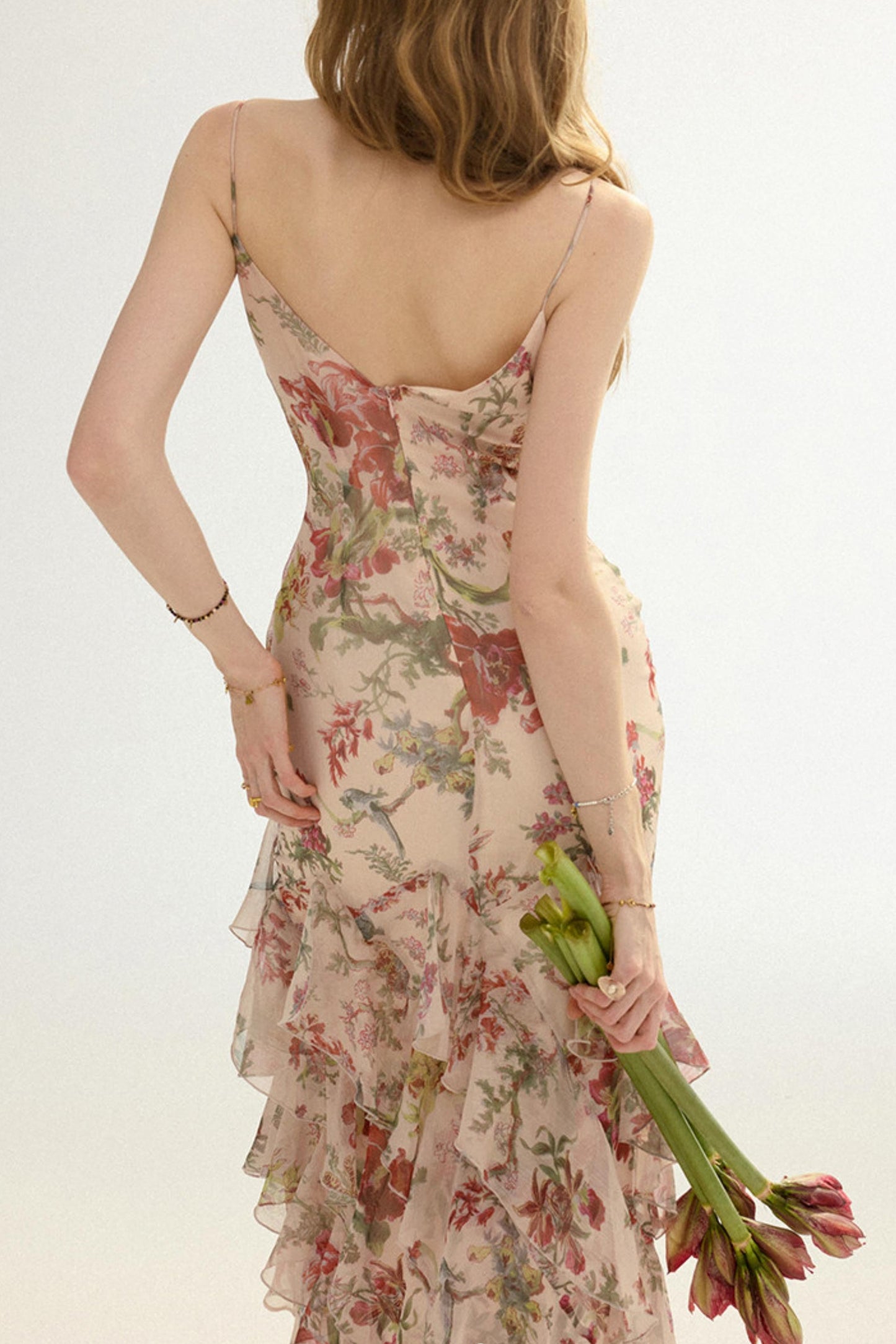 Woman wearing a floral dress holding tulips against a light background