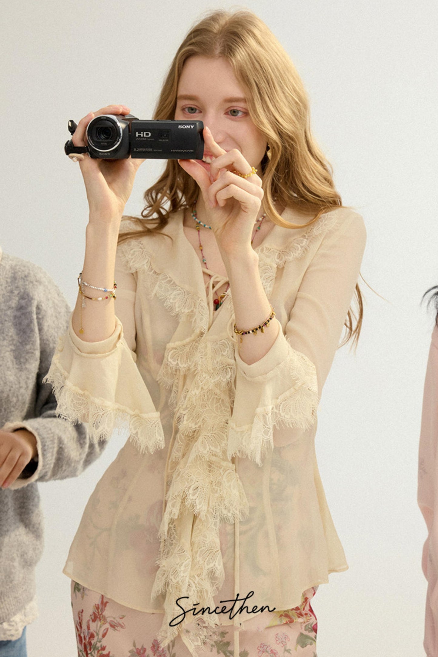 Woman holding a camera with a plain background