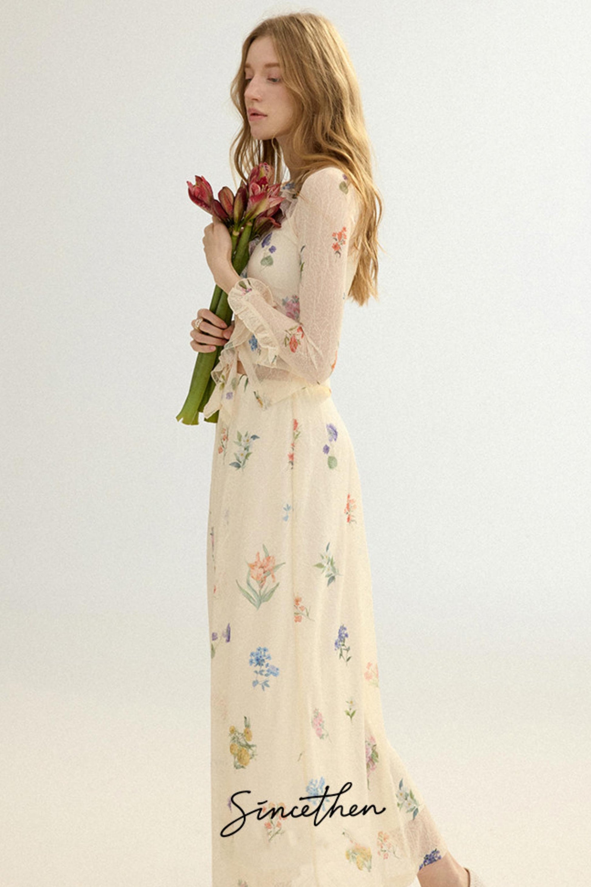 Woman in a floral dress holding flowers against a white background