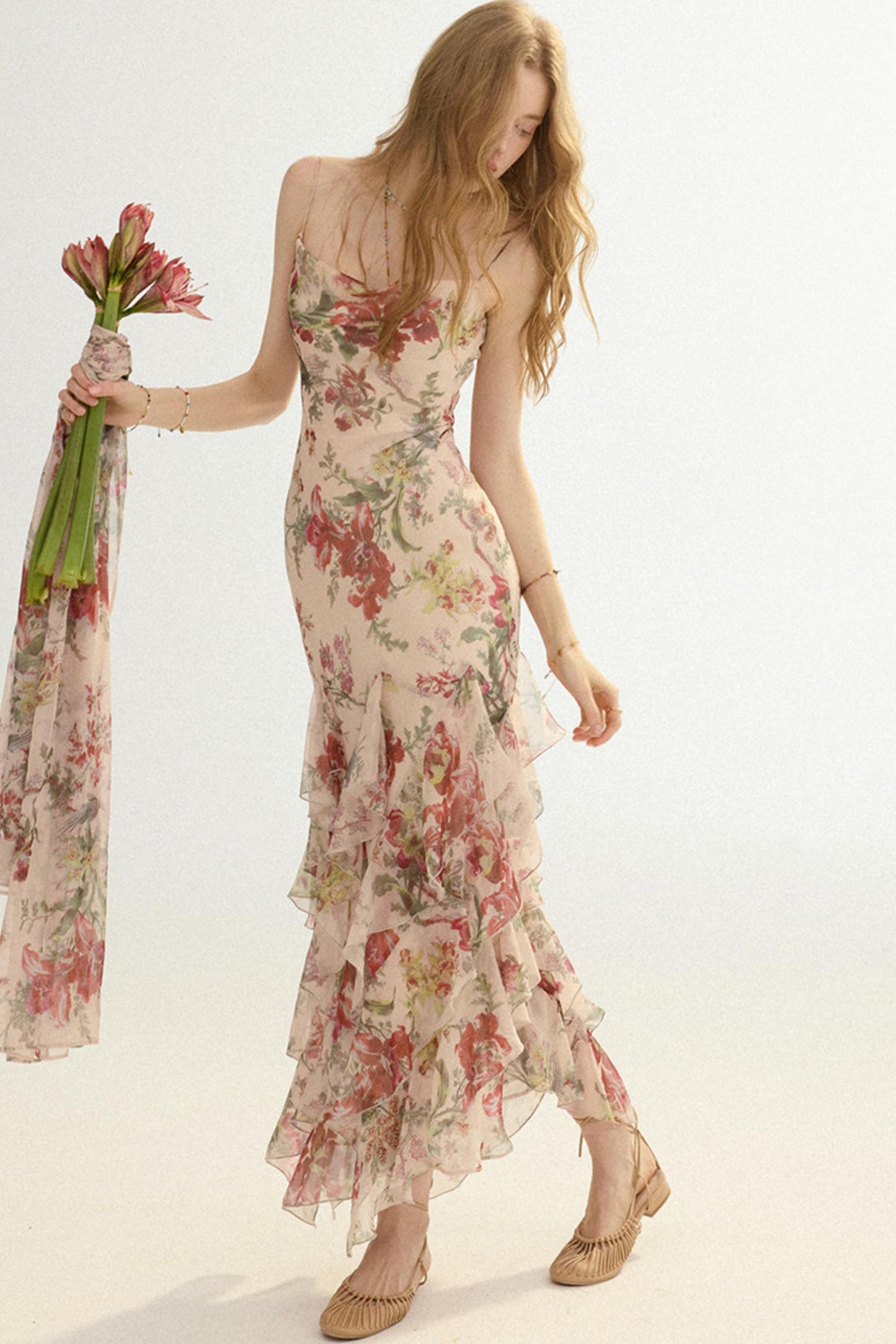 Woman wearing a floral dress holding a matching scarf against a white background