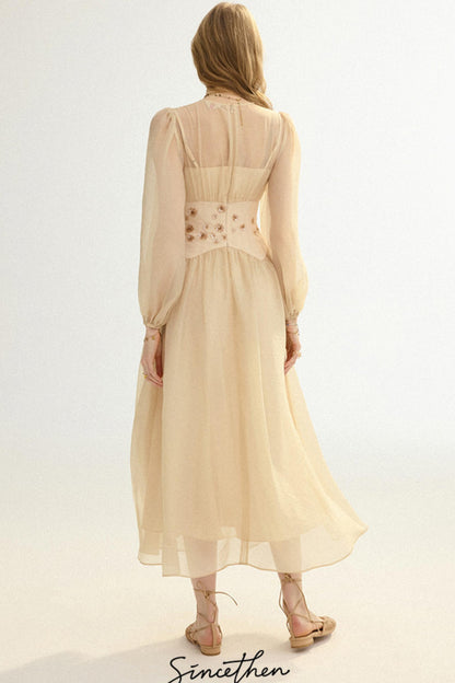 Woman wearing a beige dress with long sleeves and a belt on a white background, brand 'Sineethen' visible.