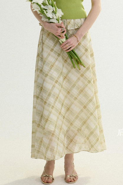 Person wearing a green top and plaid skirt holding white flowers on a white background