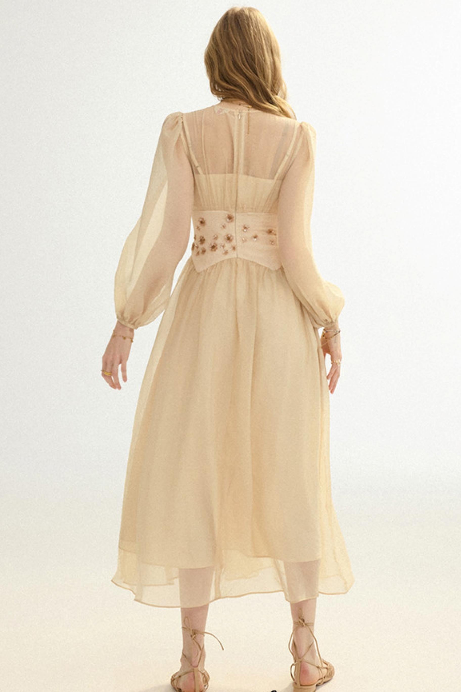 Woman wearing a beige dress with floral embellishments on a white background