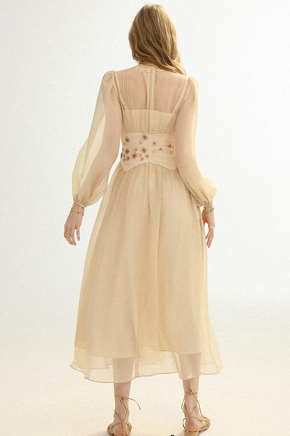 Woman wearing a beige dress with floral embellishments on a white background