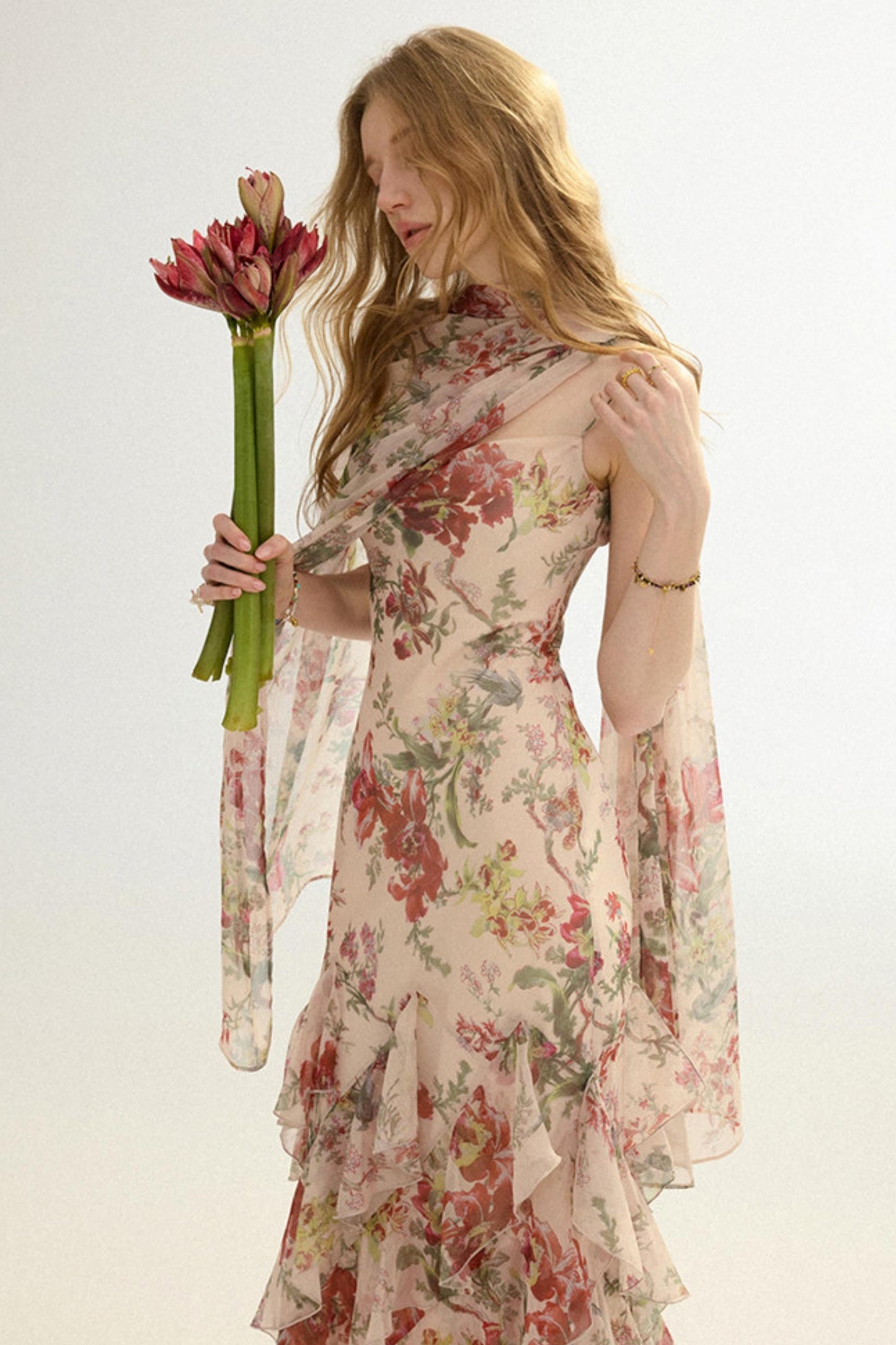 Woman in a floral dress holding flowers against a white background