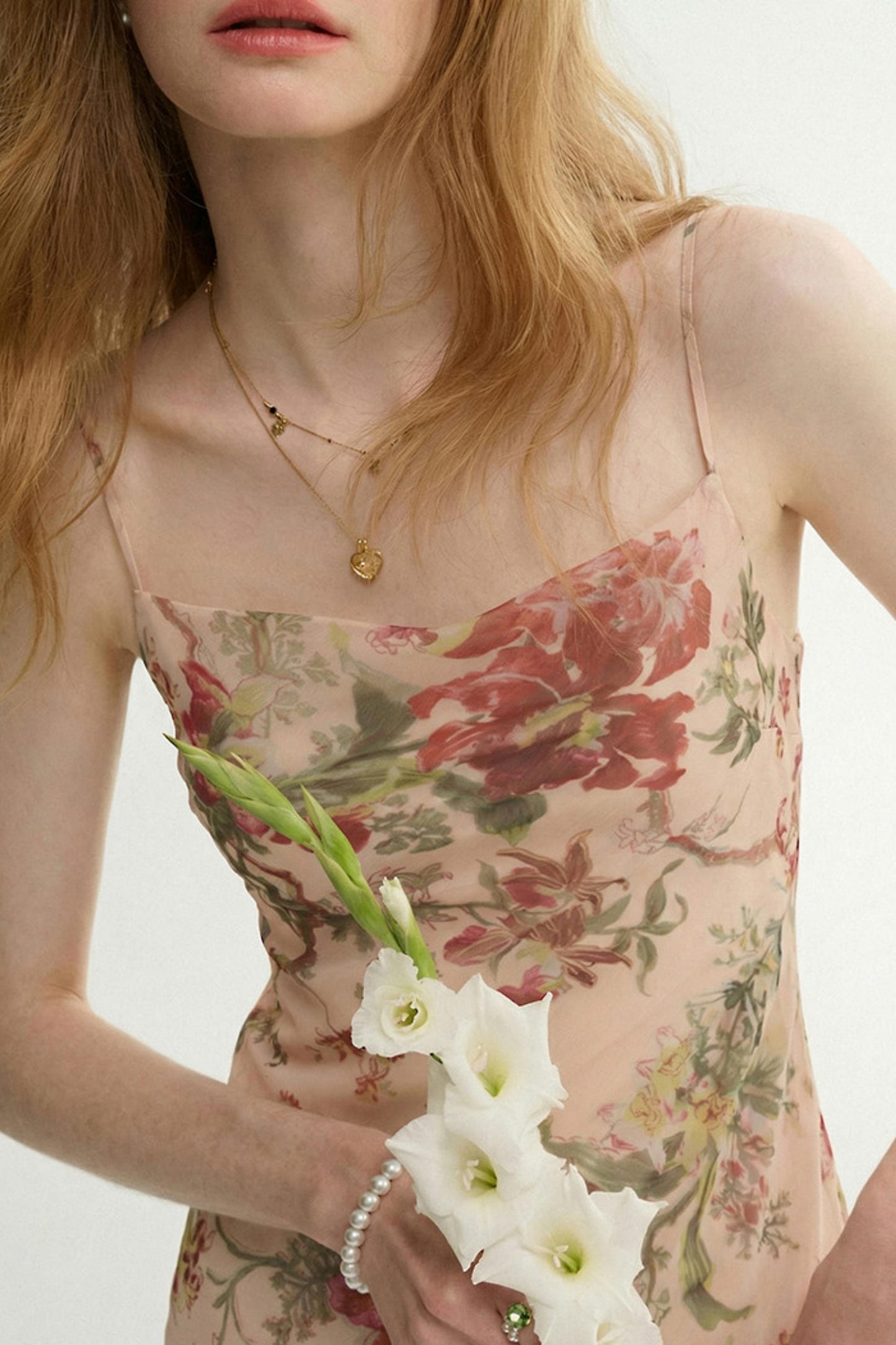 Woman wearing a floral dress holding white flowers with a blurred background